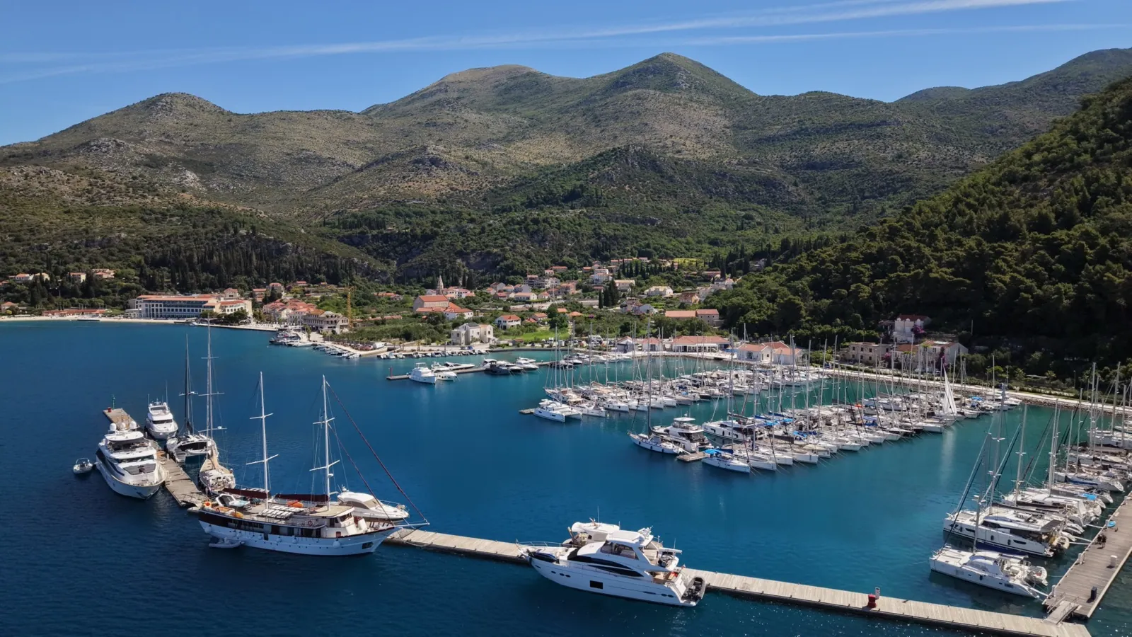 Marina w Chorwacji z lotu ptaka: jachty przy pomostach i góry w tle