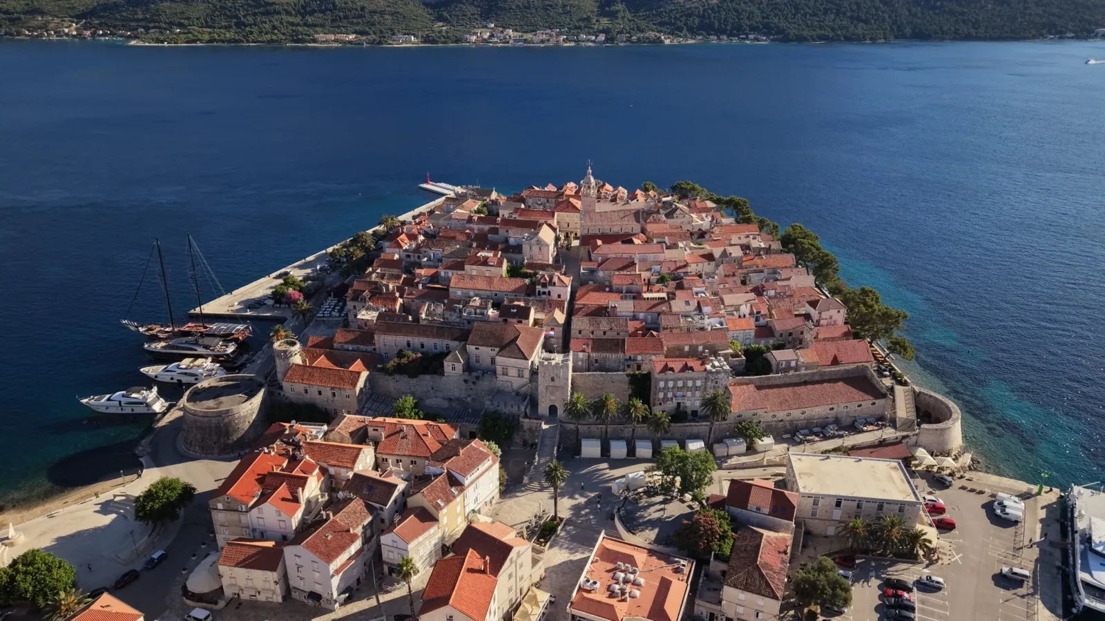 Stare miasto na półwyspie w Chorwacji z lotu ptaka: czerwone dachy, mury obronne i port